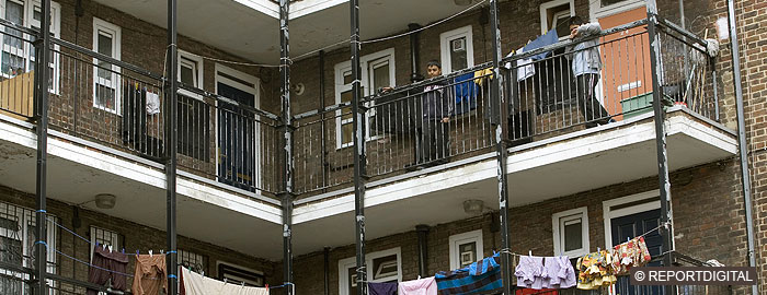 Two children looking over a balcony in a block of flats